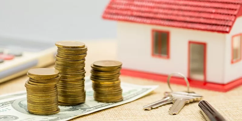Cost of building a house vs buying a home with money, coins, house model and keys